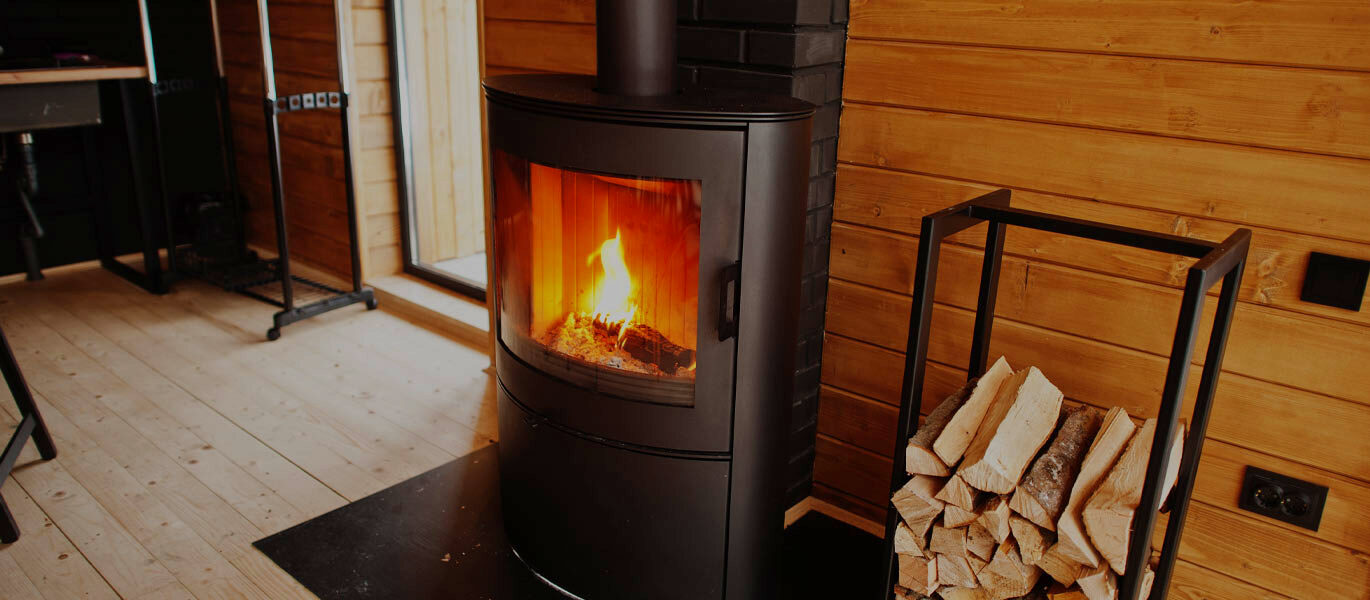 A wood-burning stove alight in a timber-clad room