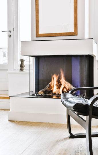 A three-sided gas fire set into a white chimney breast